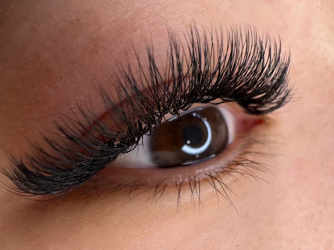 Close-up of a brown eye showing the curl and separation of lash extensions